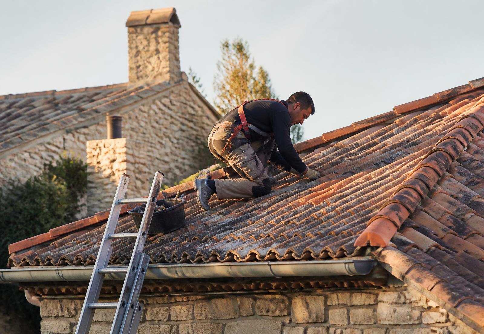Couvreur professionnel travaillant sur la toiture en tuiles d’une maison française
